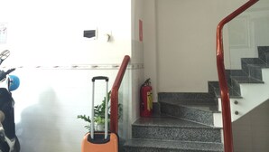 A staircase with a glass railing, a fire extinguisher, and a framed picture on the wall. - Hotel Thu Thao (Phan Rang)