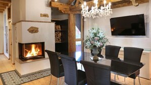 Un comedor con chimenea, vigas de madera y una araña.