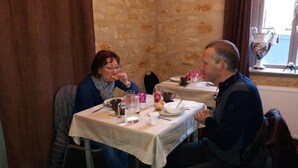 Un coin repas avec des murs en pierre, une table dressée avec des assiettes, des tasses et des couverts.