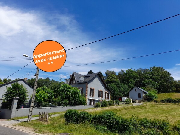 A residential area with houses, a clear sky, and a sign indicating 'Appartement avec cuisine.'