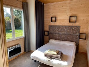 A bedroom with a bed, a window with curtains, a radiator, and a decorative headboard. - Near Soulac-sur-Mer, 6-bedroom villa with heated indoor pool, jacuzzi, and sauna (Grayan-Et-L'hôpital)