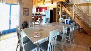 A spacious dining area with a high wooden ceiling and a view of the kitchen in the background. - Near Soulac-sur-Mer, 6-bedroom villa with heated indoor pool, jacuzzi, and sauna (Grayan-Et-L'hôpital)