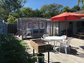 A patio with a glass enclosure, white chairs, a barbecue grill, and a red umbrella. - Near Soulac-sur-Mer, 6-bedroom villa with heated indoor pool, jacuzzi, and sauna (Grayan-Et-L'hôpital)