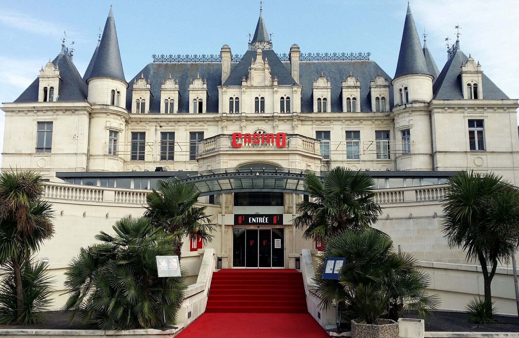 A grand building with a red carpet entrance, a sign reading "Casino", and a staircase leading up to the entrance.
