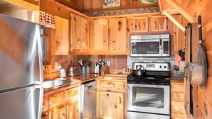A kitchen with wooden cabinets, stainless steel appliances, and a checkered cloth hanging over the sink.