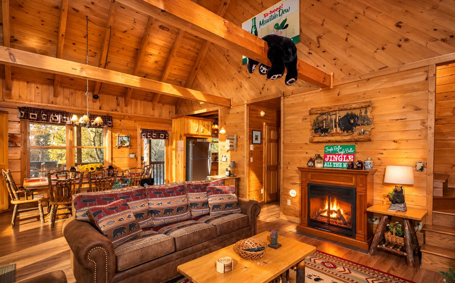 A cozy log cabin interior with a sofa, fireplace, dining area, and wooden walls.