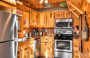 A kitchen with wooden cabinets, stainless steel appliances, and a checkered cloth hanging on the door.