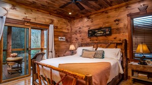 A wooden cabin bedroom with a bed, a nightstand, a lamp, and a window with curtains.