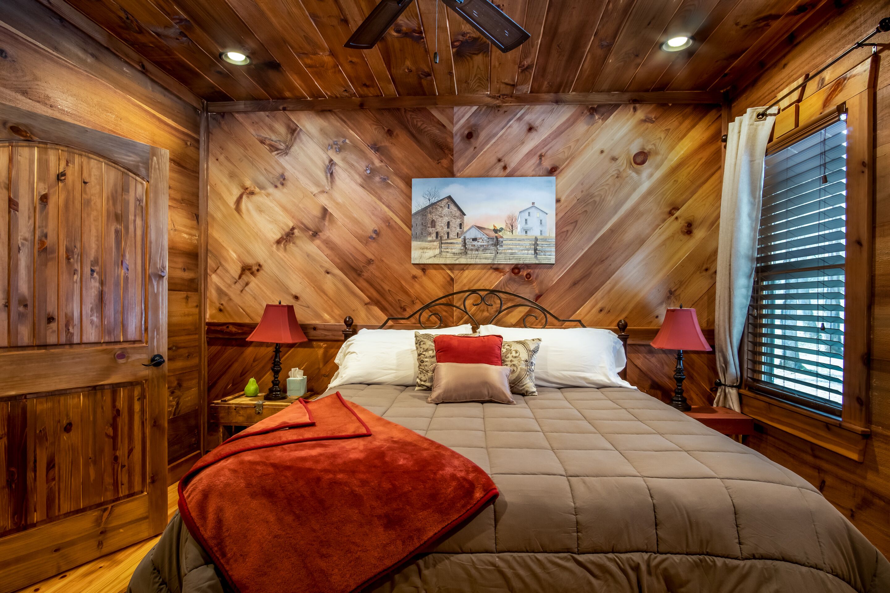 A wooden-paneled bedroom with a bed, two bedside tables, and a painting on the wall.
