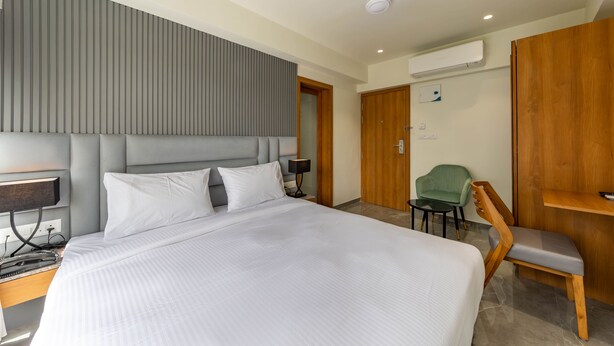 Una habitación de hotel moderna con una cama grande, un escritorio, una silla y una mesita.