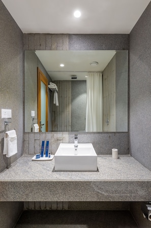Un baño moderno con un espejo grande, un lavabo blanco y un perchero para toallas.