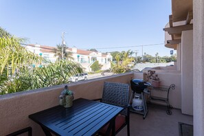 Ein Balkon mit Tisch, Stühlen, einem Grill und einem Blumentopf.