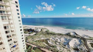 A beachfront hotel with multiple balconies, a sandy beach, and a clear view of the ocean.