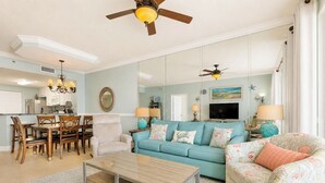 A living room with a sofa, armchair, coffee table, and a dining area with chairs and a table.