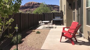 Eine Terrasse mit Grill, Sitzgelegenheit und Blick auf rote Felsformationen.