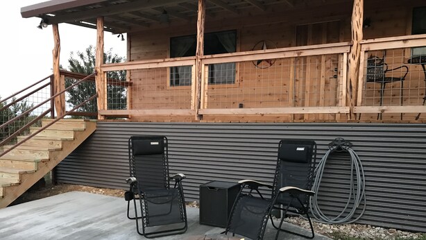 A wooden cabin with a stone fire pit and two folding chairs. - New lower rates. Great reviews   Elevated deck, Pet friendly, Romantic scenic (Fredericksburg)