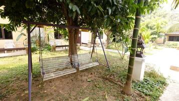A garden area with a swing set, benches, and a small tree.