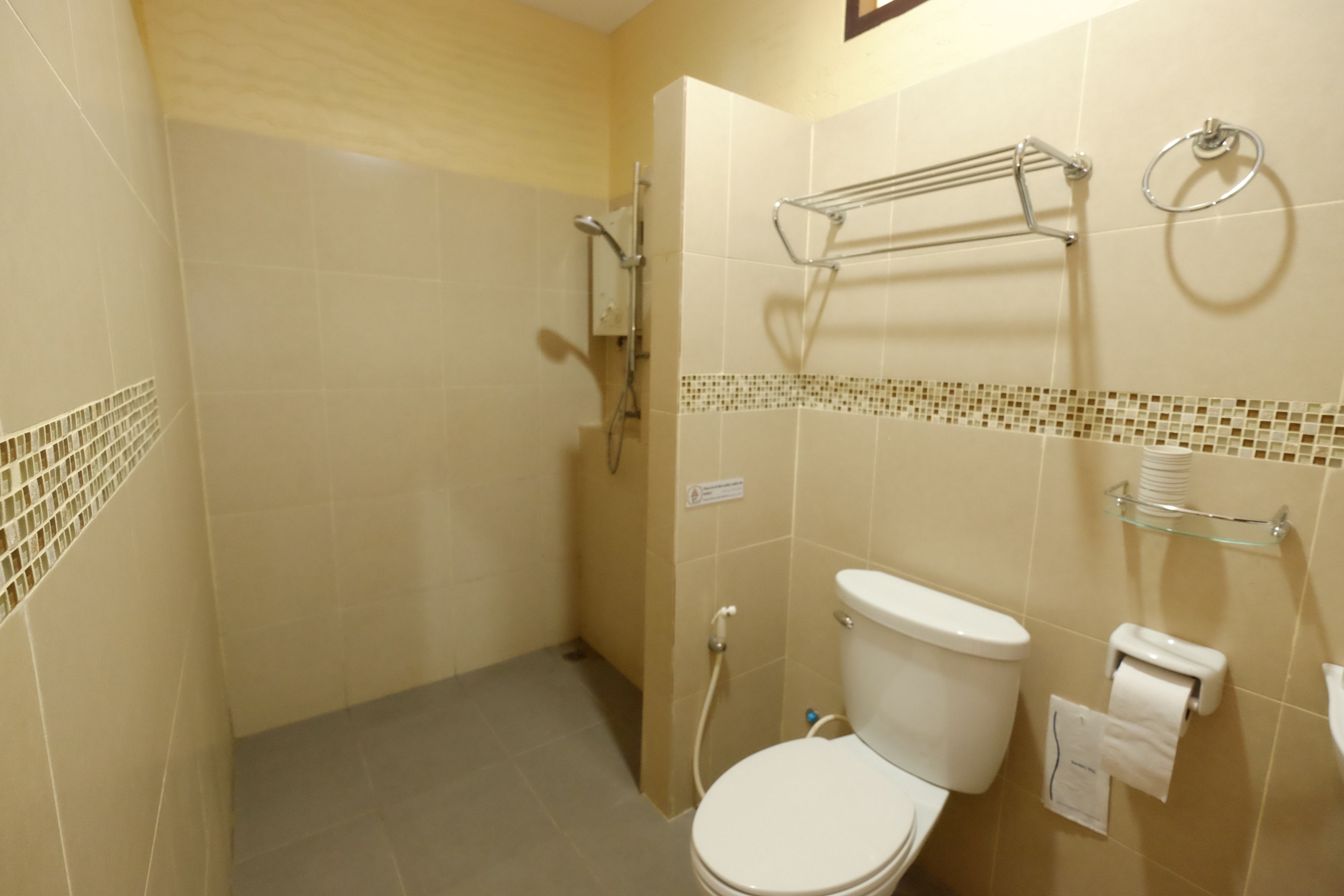 Un baño con inodoro, ducha y barra para toallas.