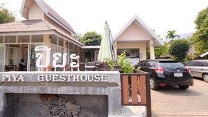 Majatalo nimeltä ”PIYA GUESTHOUSE”, jossa on kyltti, ulkona oleva oleskelualue ja parkissa olevia autoja.