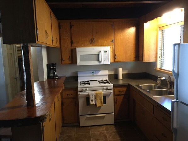 A kitchen with wooden cabinets, a microwave, a gas stove, and a sink. - Walking distance to Snow Summit Resort. (Big Bear Lake)