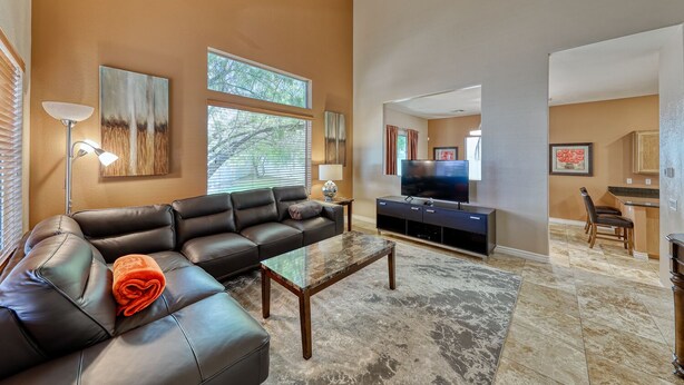 A living room with a sofa, a coffee table, a TV, and a kitchen area visible through an open doorway. - Why stay in the confinement of a hotel,when you can stay in this Las Vegas oasis (Las Vegas)