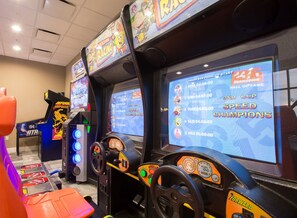 Uma fileira de máquinas de jogos de corrida com telas exibindo pontuações de jogos e o título 'Speed Champions'.
