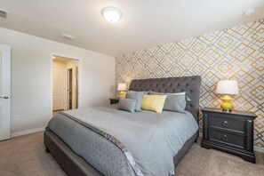 A bedroom with a bed, nightstands, and a patterned wall. - Vacation Home: 6BR w/ Pool + Game Room near Disney (Kissimmee)