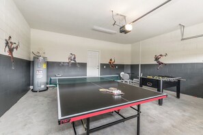 Une pièce équipée d’une table de ping-pong, d’un baby-foot et d’un chauffe-eau.