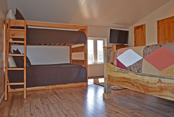 A bunk bed with a ladder, a television on a stand, and a window with a view of trees. - Majestic Lodge only 22 miles from the base of Pike's Peak (Woodland Park)