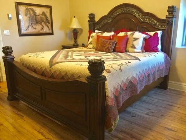 A bed with a quilt and pillows, a nightstand with a lamp, and a framed picture on the wall. - Majestic Lodge only 22 miles from the base of Pike's Peak (Woodland Park)