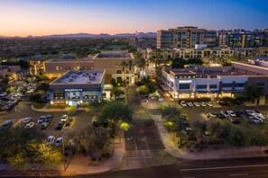 Une zone commerciale avec un parking, des bâtiments et un coucher de soleil en arrière-plan.