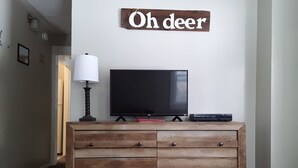 Ein Wohnzimmer mit einem Holzkasten, einem Fernseher und einem Schild mit der Aufschrift 'Oh deer'.