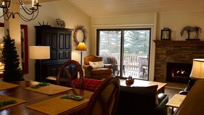 A cozy living room with a fireplace, a dining area with a table set for four, and a comfortable seating area with a sofa and armchairs. - 3 BR/BA End Unit, Lg Decks, Views (Sun Valley)
