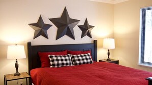 A bedroom with a red bedspread, two checkered pillows, a dark headboard, and three star decorations on the wall. - 3 BR/BA End Unit, Lg Decks, Views (Sun Valley)