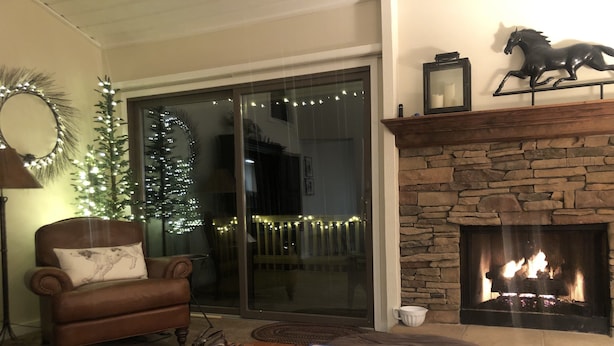 A cozy living room with a fireplace, a leather armchair, a coffee table with books and a plant, and a Christmas tree with lights. - 3 BR/BA End Unit, Lg Decks, Views (Sun Valley)
