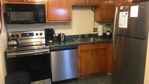 A compact kitchen with wooden cabinets, a stainless steel refrigerator, a microwave, a coffee maker, and a dishwasher. - 'Silvercreek Escape' 2BR Silvercreek, Ski-in/Ski-out!!!!!           (Snowshoe)
