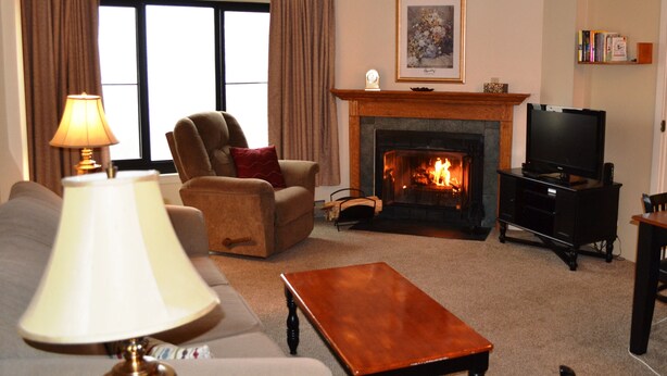 A living room with a fireplace, a television, a sofa, a chair, and a lamp. - 'Silvercreek Escape' 2BR Silvercreek, Ski-in/Ski-out!!!!!           (Snowshoe)