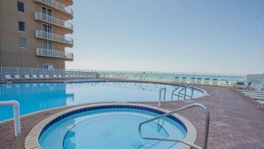 Ein Pool mit Backsteindeck, einer kleinen Whirlpool-Haftung und Liegestühlen.