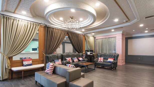 A spacious room with a large seating area featuring sofas and armchairs, a wooden bench, and a coffee table. - Back Home Hotel (Chiayi City)