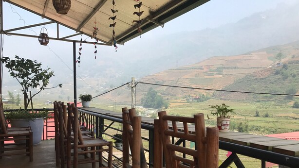 A wooden deck with chairs and potted plants, overlooking a hilly landscape. - Moc Anh House (Ta Van)