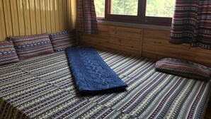 A room with a bed, patterned bedding, wooden walls, a window, and curtains. - Moc Anh House (Ta Van)