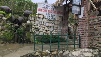 A rustic building with a stone wall and a signboard advertising a cafe and vegetarian food.
