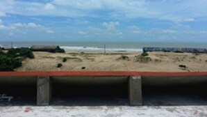 Una spiaggia con una barriera in cemento e una zona sabbiosa con vegetazione rada.