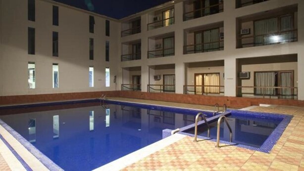 Una piscina con bordo piastrellato, circondata da un edificio con numerosi balconi e finestre.