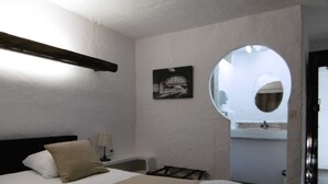 A bedroom with a bed, a bedside table, a lamp, a picture on the wall, and a bathroom visible through an archway. - Relais Des Vieilles Postes (Les Avenieres-Veyrins-Thuellin)