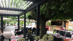 An outdoor dining area with tables and chairs, surrounded by greenery and a pergola structure. - Relais Des Vieilles Postes (Les Avenieres-Veyrins-Thuellin)