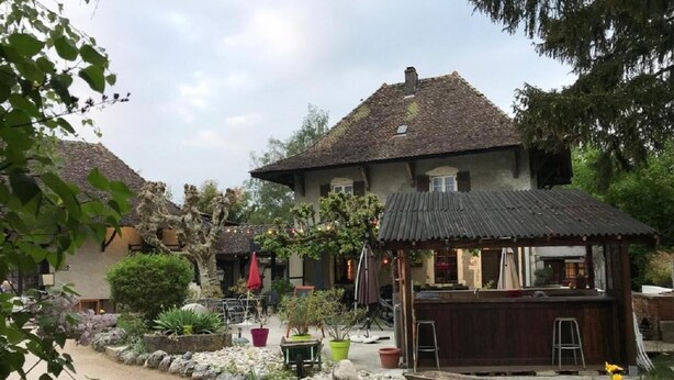 A rustic building with a thatched roof, surrounded by a garden with various potted plants and a small wooden dock. - Relais Des Vieilles Postes (Les Avenieres-Veyrins-Thuellin)