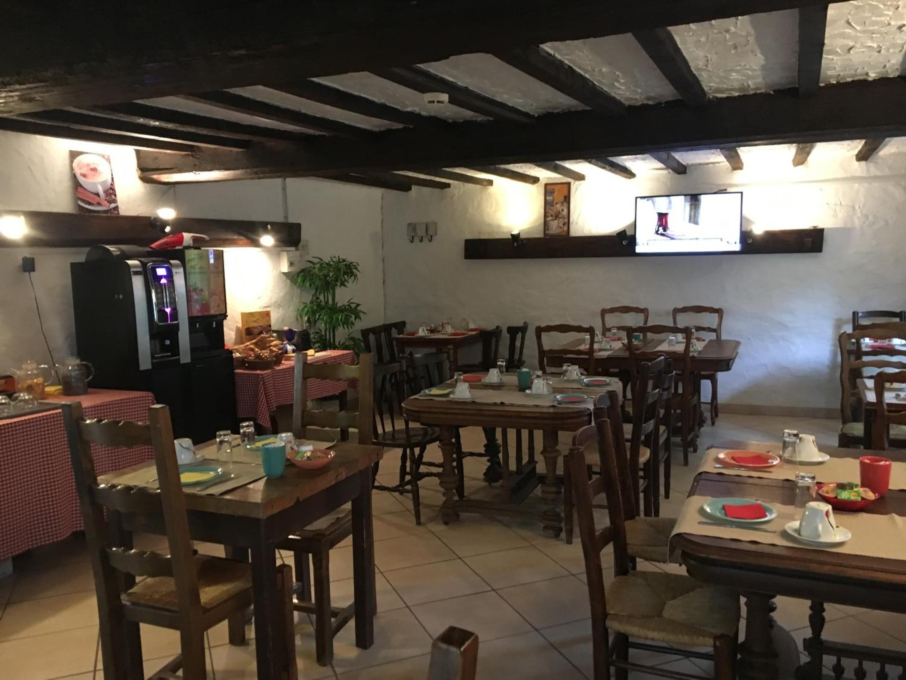 Un restaurant avec des tables et des chaises en bois, un appareil à café et un écran de télévision fixé au mur.