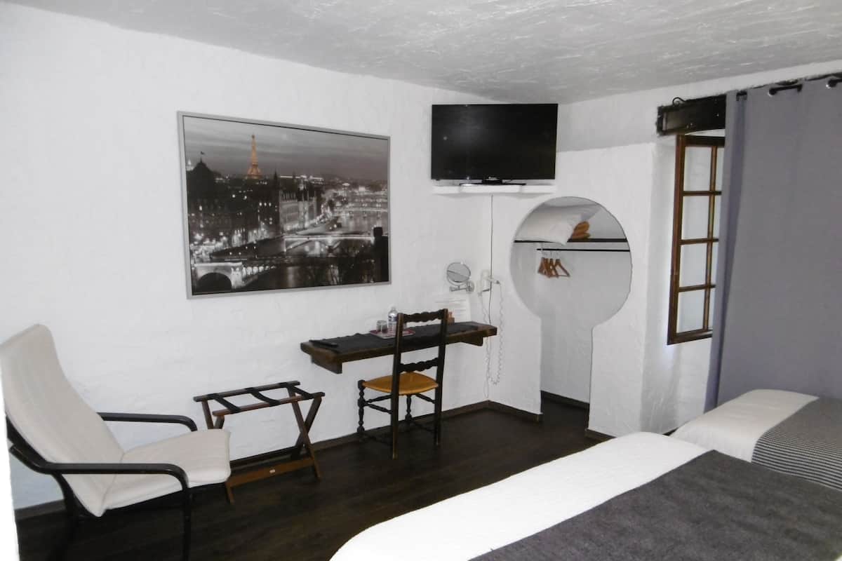 Une chambre d’hôtel comprenant un lit, un bureau avec une chaise, une télévision, une fenêtre et un tableau accroché au mur.