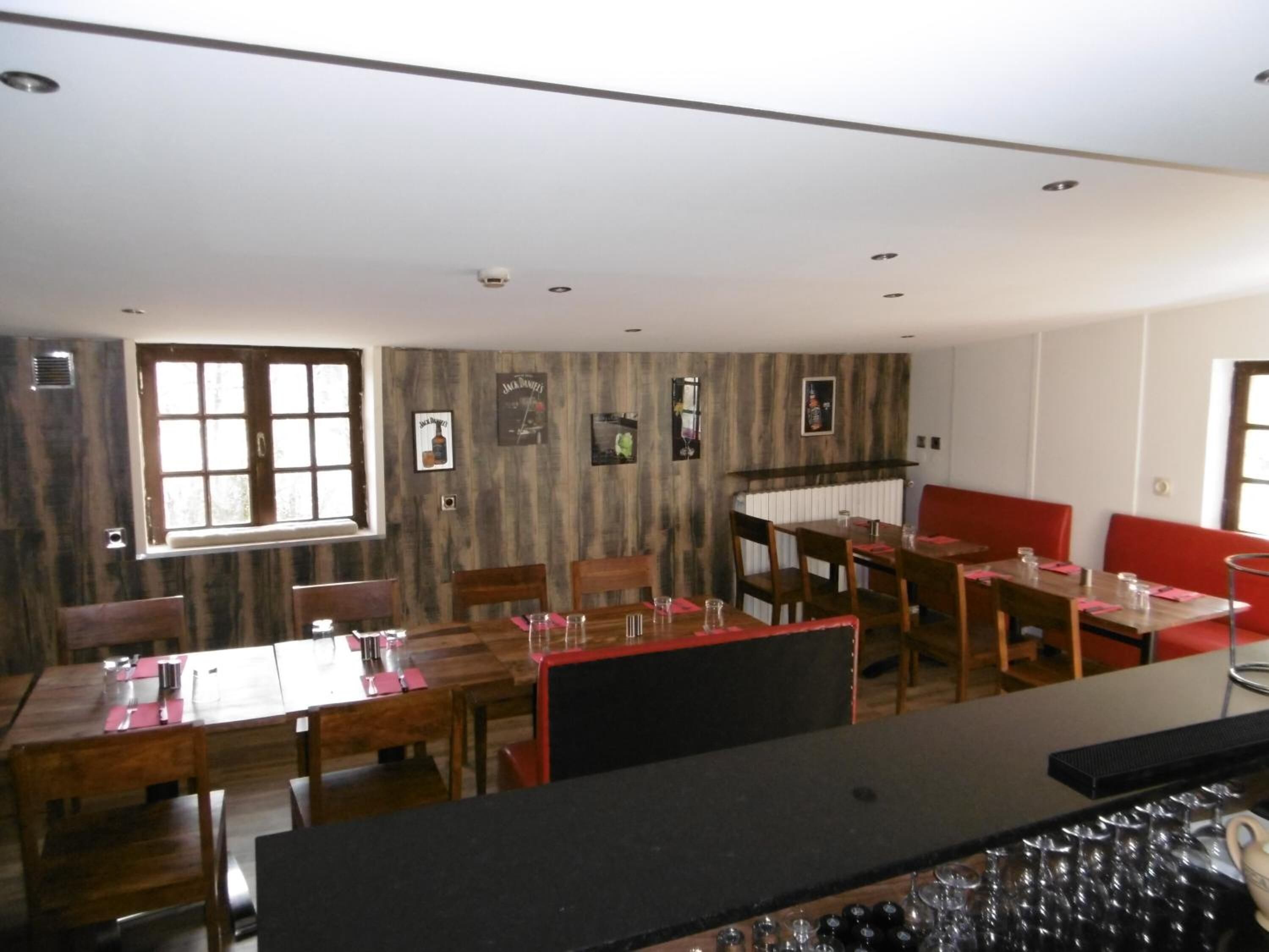 A restaurant with wooden tables and chairs, a bar area, and a view of the street.